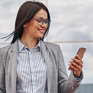 Studentin schaut lächelnd auf ihr Handy, während sie ihr Studium in der EU plant