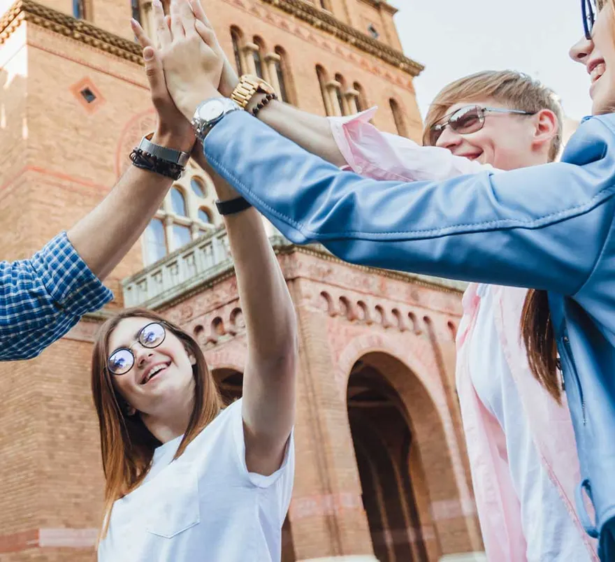 Studierende jubeln vor einem historischen europäischen Universitätsgebäude